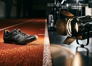 A professional running shoe on a track lane next to a studio light.