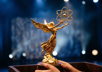 A close-up of an Emmy statuette against a blue light background