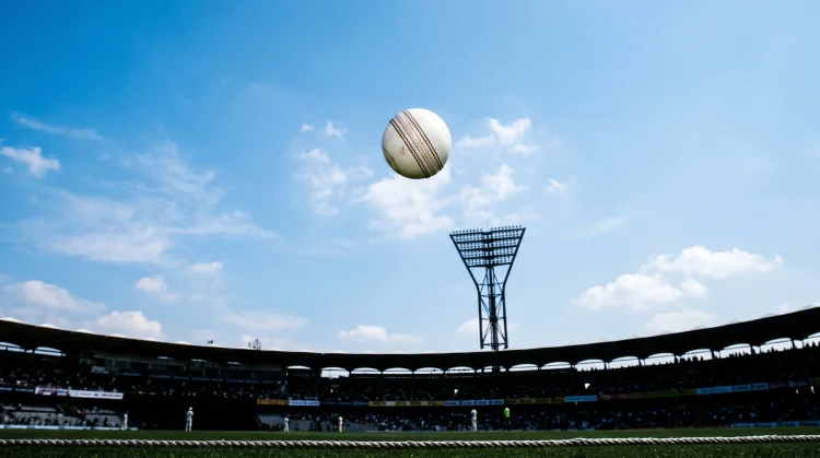 A white cricket ball in flight against a bright sky.
