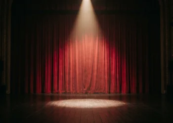 A spotlight on a closed stage curtain symbolizing a broadcast boycott.