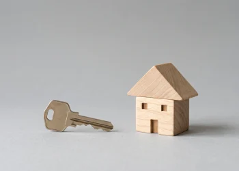 A house key and a small wooden model of a house.