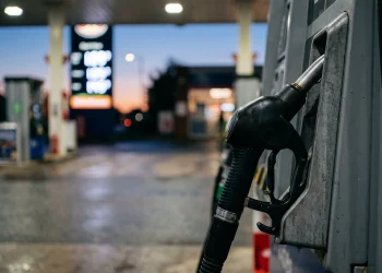 Close-up of a fuel pump nozzle at a petrol station at night.