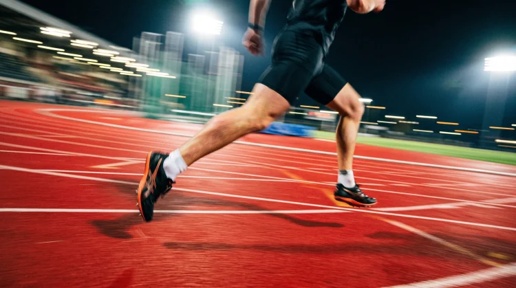 Low angle shot of a sprinter's legs in motion on a running track.