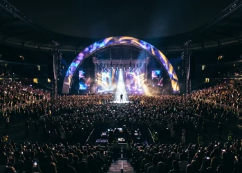 Conceptual image of a large stadium performance with bright lights and a stage silhouette.