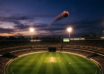 A cricket ball flying through the air under stadium floodlights.