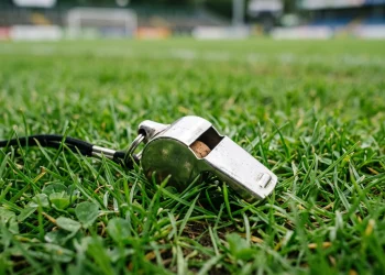 A referee's whistle on the grass of a football pitch.
